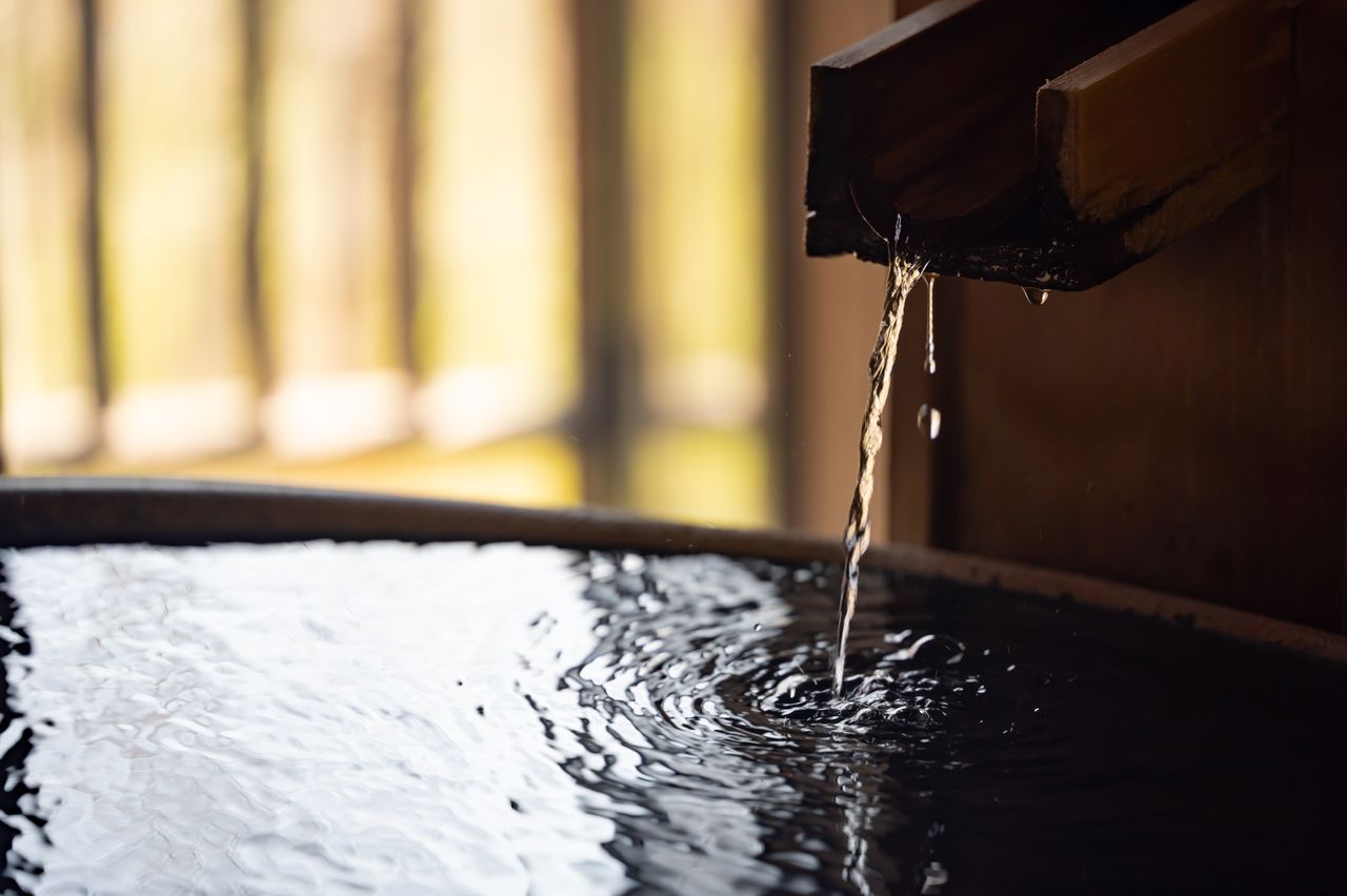 Thermalwasser fließt aus einer Holzleitung in ein Becken