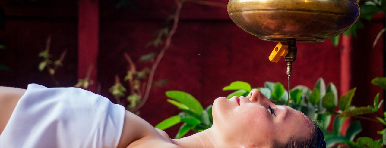 Frau bekommt den ayurvedischen Stirnguss Shirodhara