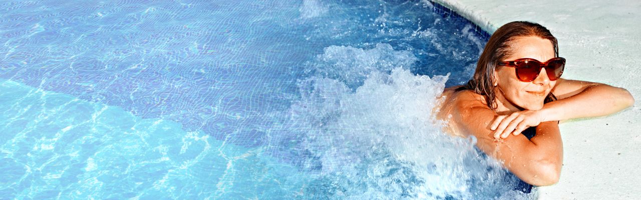 Eine Frau entspannt am Beckenrand eines Pools