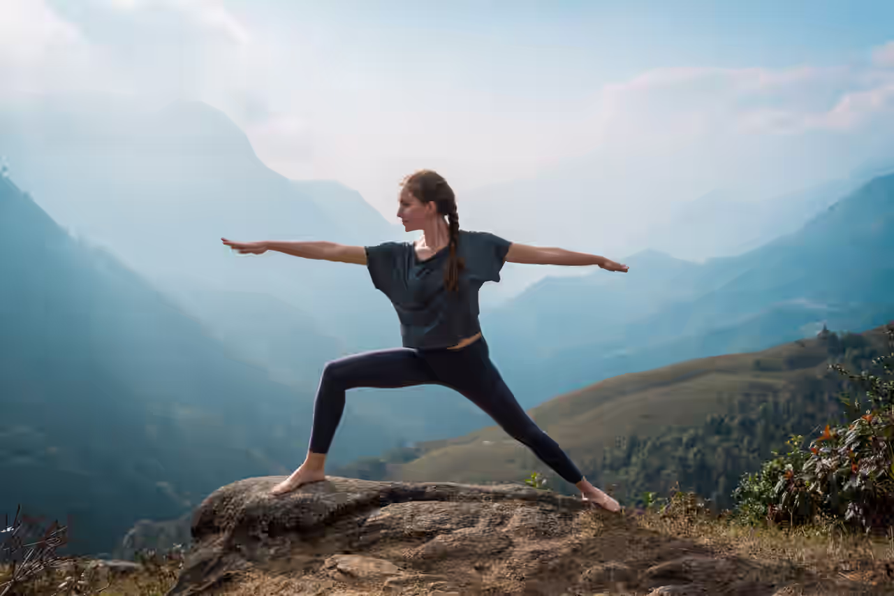 Eine Frau praktiziert Yoga auf einem Felsen in der Berglandschaft des Erzgebirges