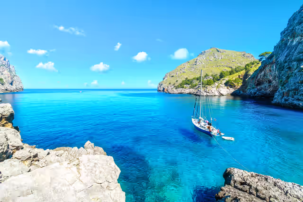 Meeresküste mit Felsen und Boot auf blauem Wasser auf Mallorca