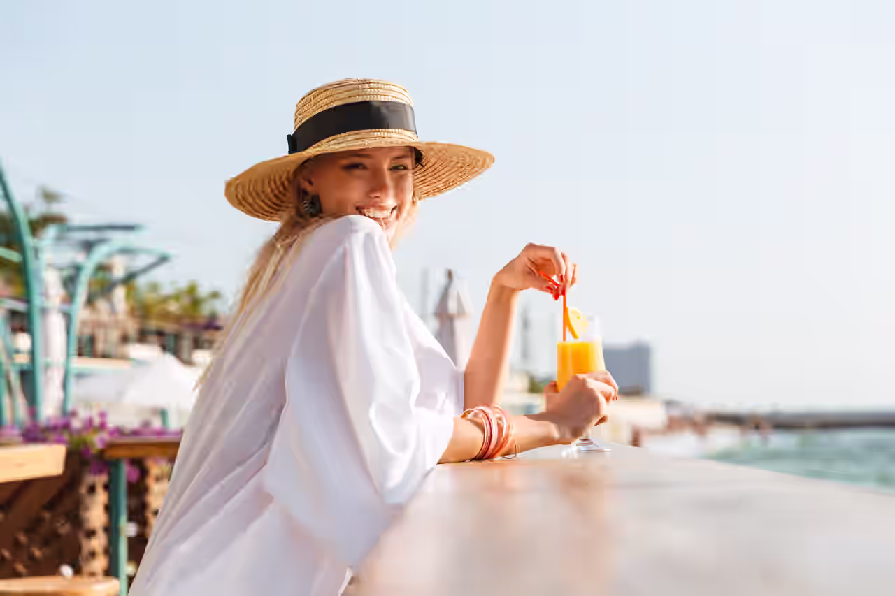 Eine Frau genießt ein Cocktail auf einer Terrasse mit Meerblick