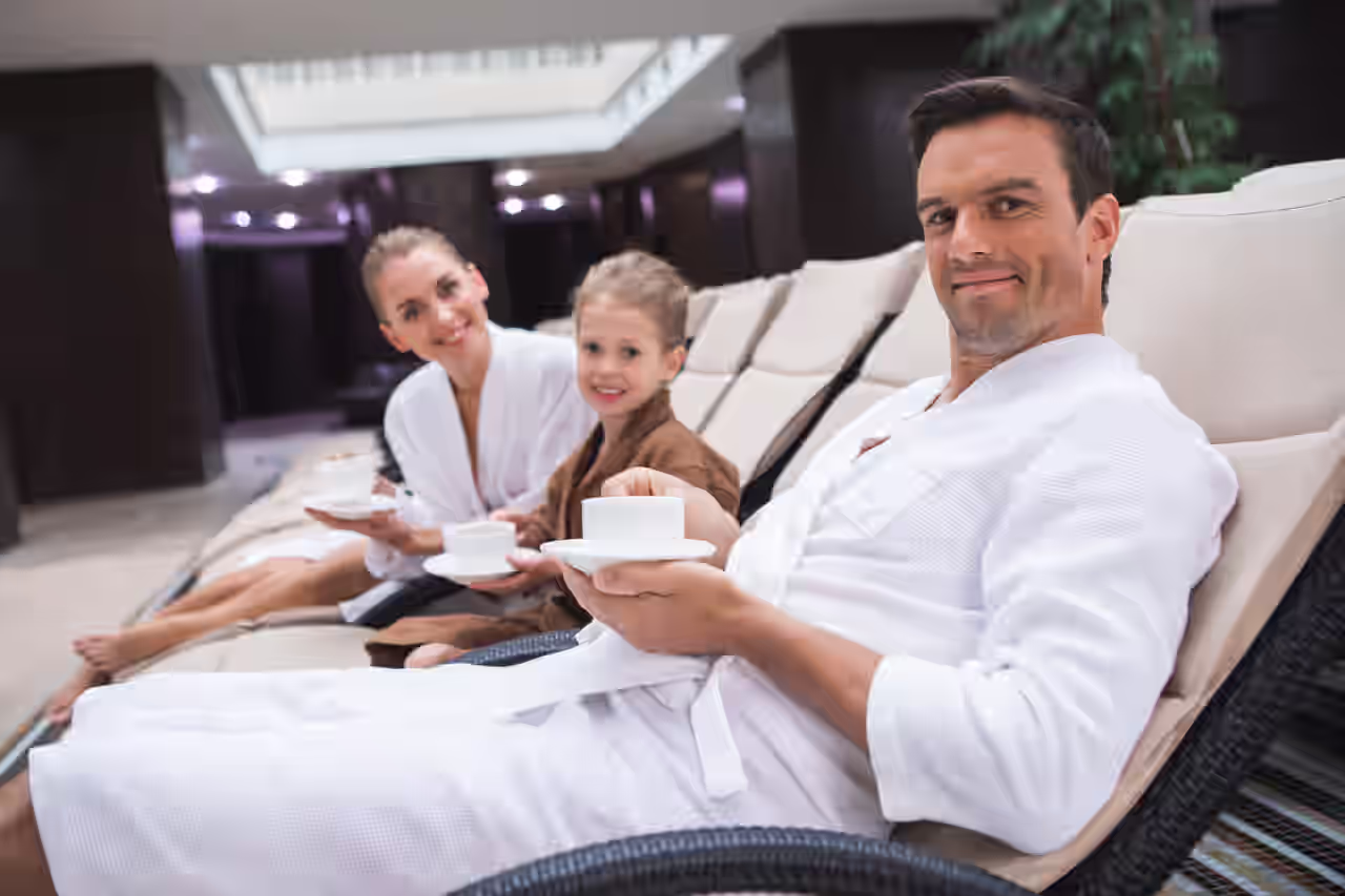 Eine Familie im Bademantel auf Liegen im Wellnessbereich