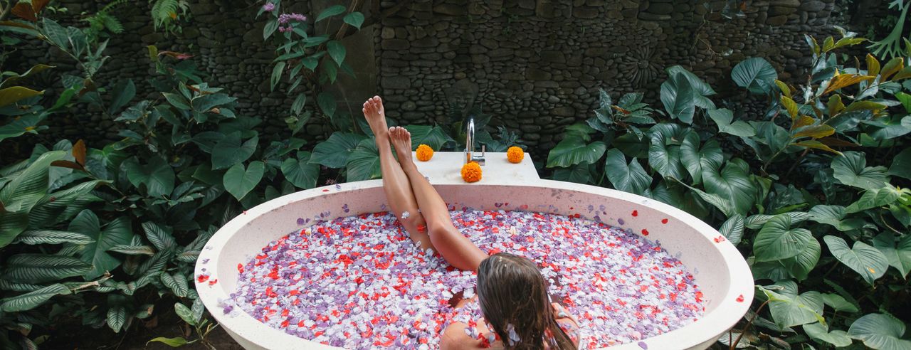 Een vrouw ontspant zich in een bad met bloemen in een spahotel