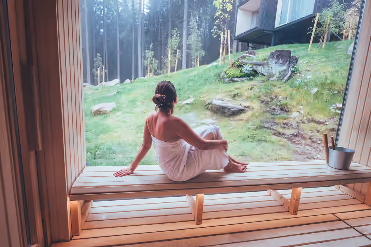Frau auf Saunabank mit Blick auf Waldregion