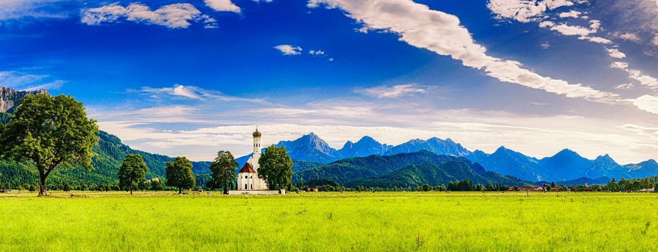 Berglandschaft, grüne Wiesen und eine Kirche bei einem Wellness Hotel in Süddeutschland