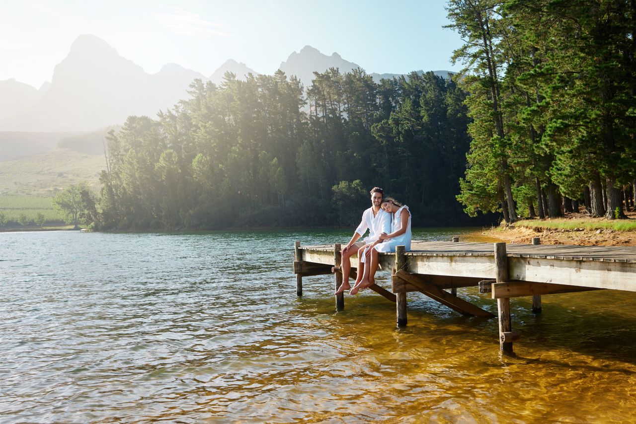 Ein Paar sitzt auf einem Steg am See in ihrem Luxusurlaub