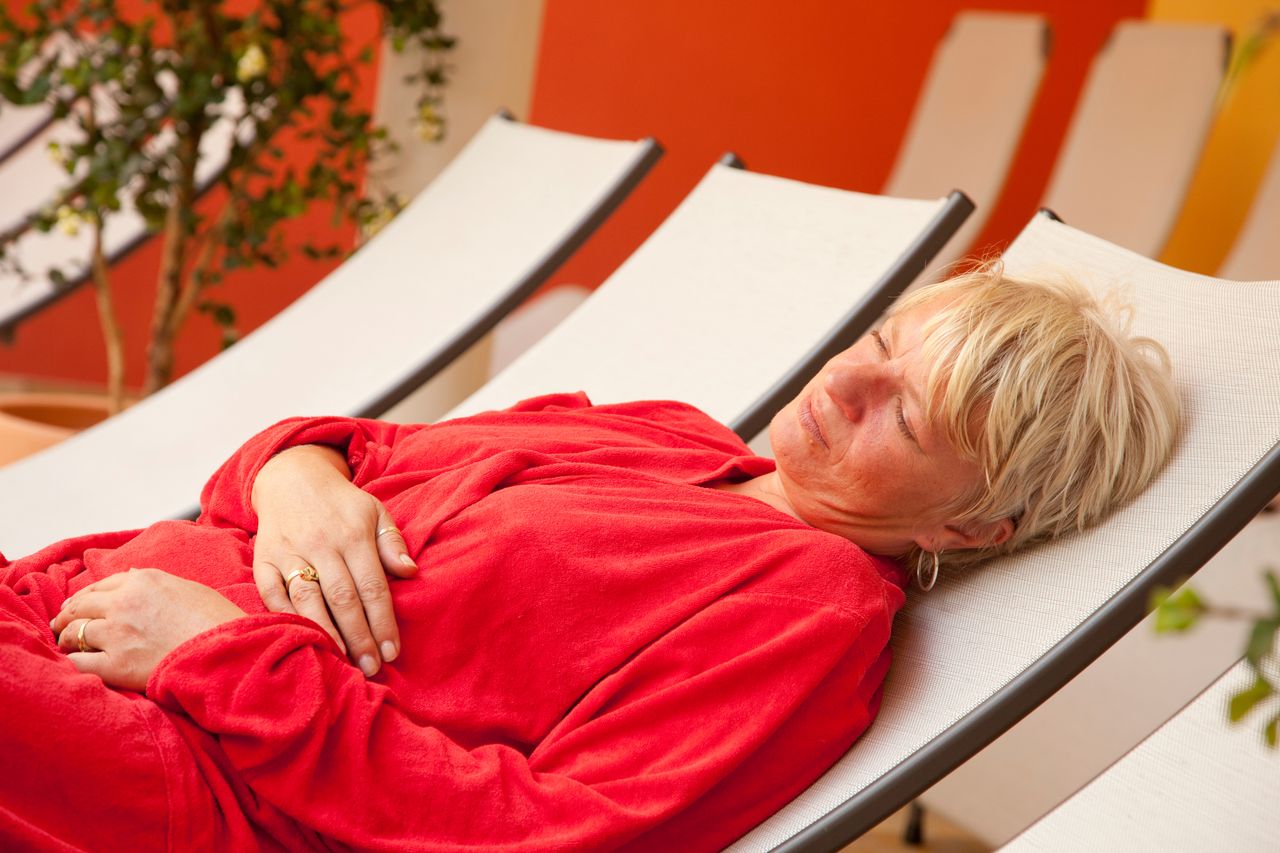 Eine Frau entspannt auf einer Liege im Wellnessbereich