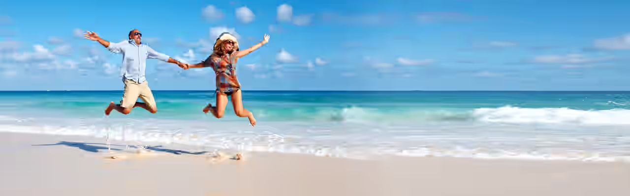 Ein Pärchen hüpft am Strand von Mallorca in die Luft
