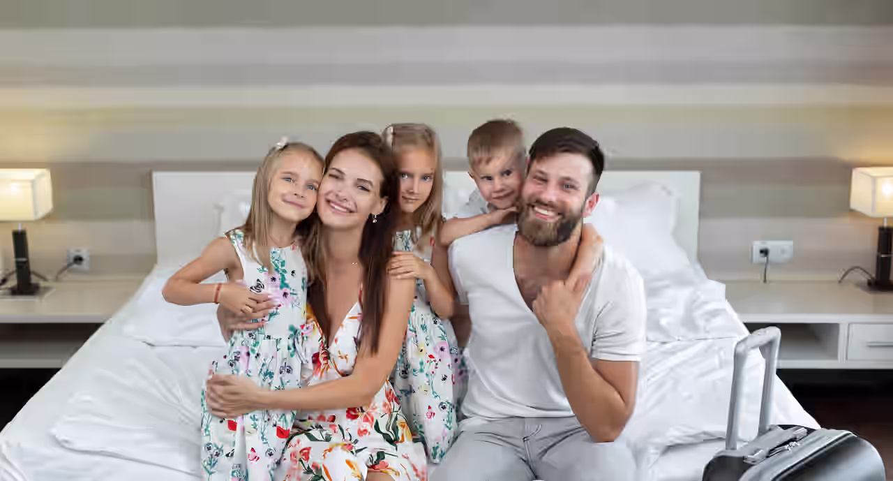 Eine Familie sitzt auf einem Doppelbett im Hotelzimmer