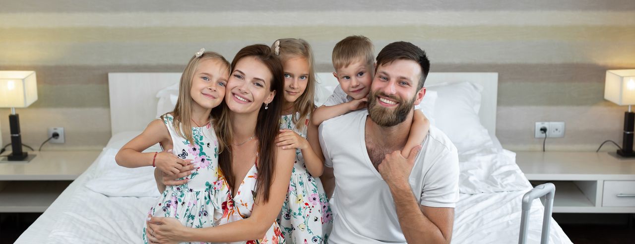 Eine Familie sitzt auf einem Doppelbett im Hotelzimmer