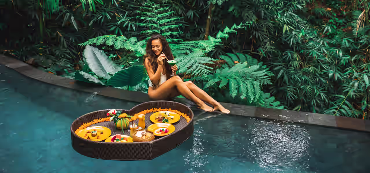 Eine Frau sitzt am Poolrand, im Becken ein schwimmendes Buffet