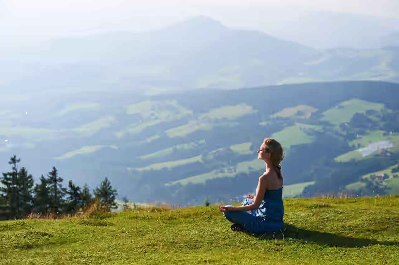 Frau, die auf einem Berg mit Bergpanorama meditiert