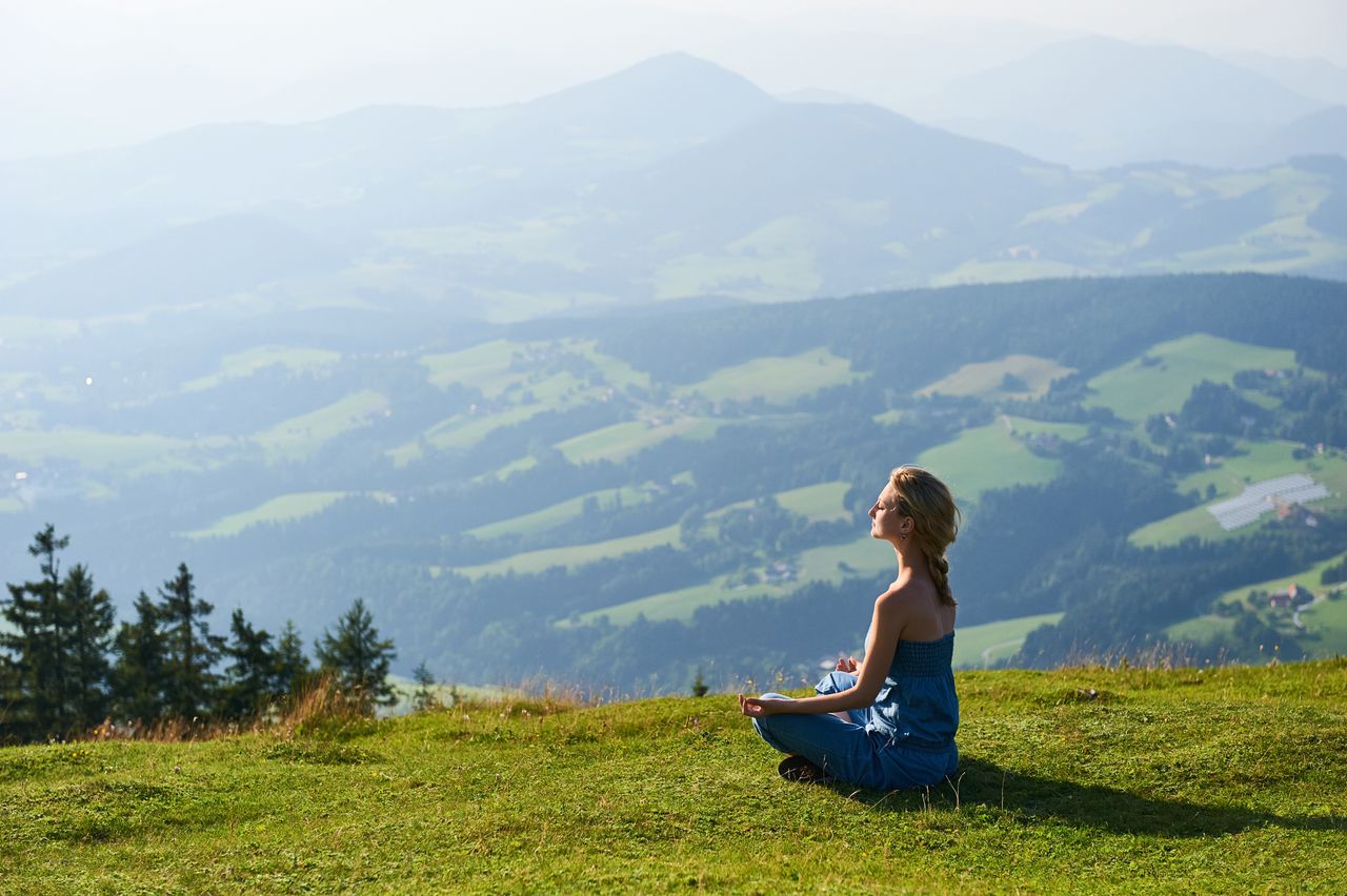 Frau, die auf einem Berg mit Bergpanorama meditiert