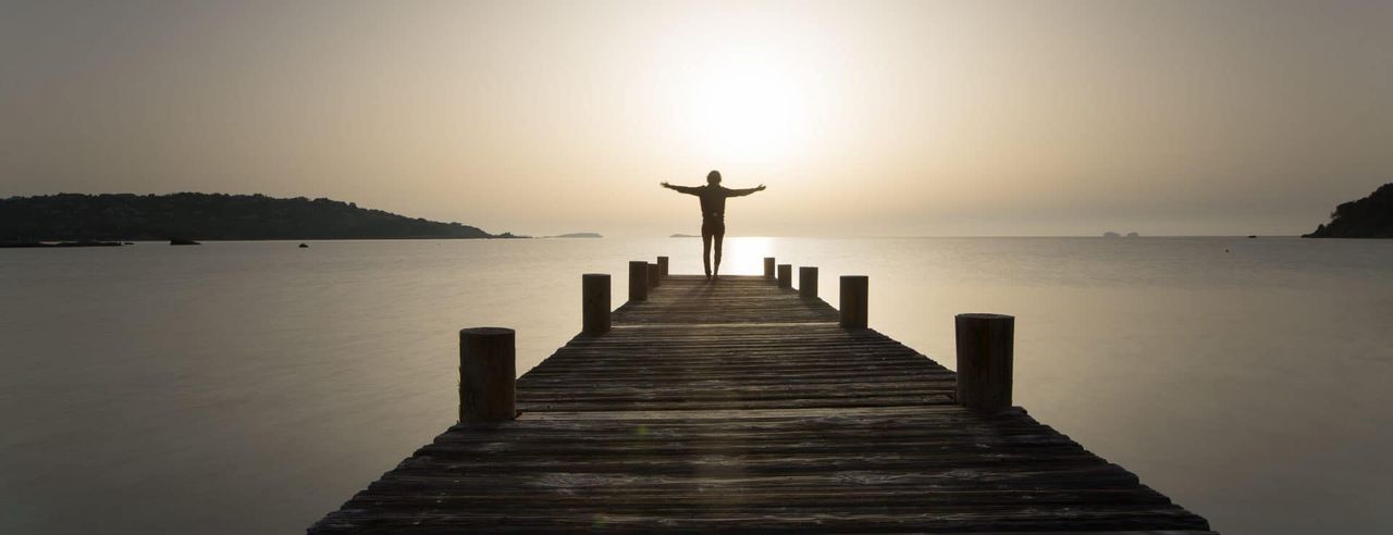 Ein Mann steht auf einer Brücke auf einem See voller Achtsamkeit
