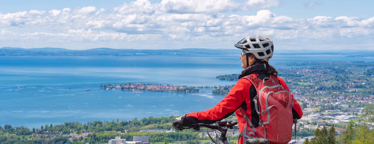 Eine Frau mit Fahrrad genießt den Blick über den Bodensee