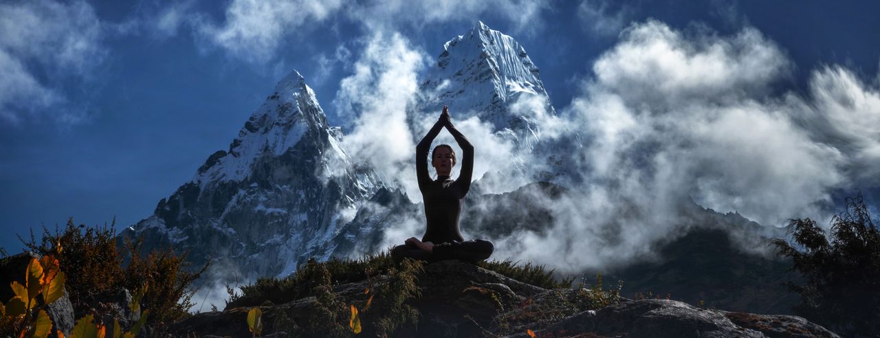 Eine Frau meditiert vor der Kulisse des Himalaya-Gebirges