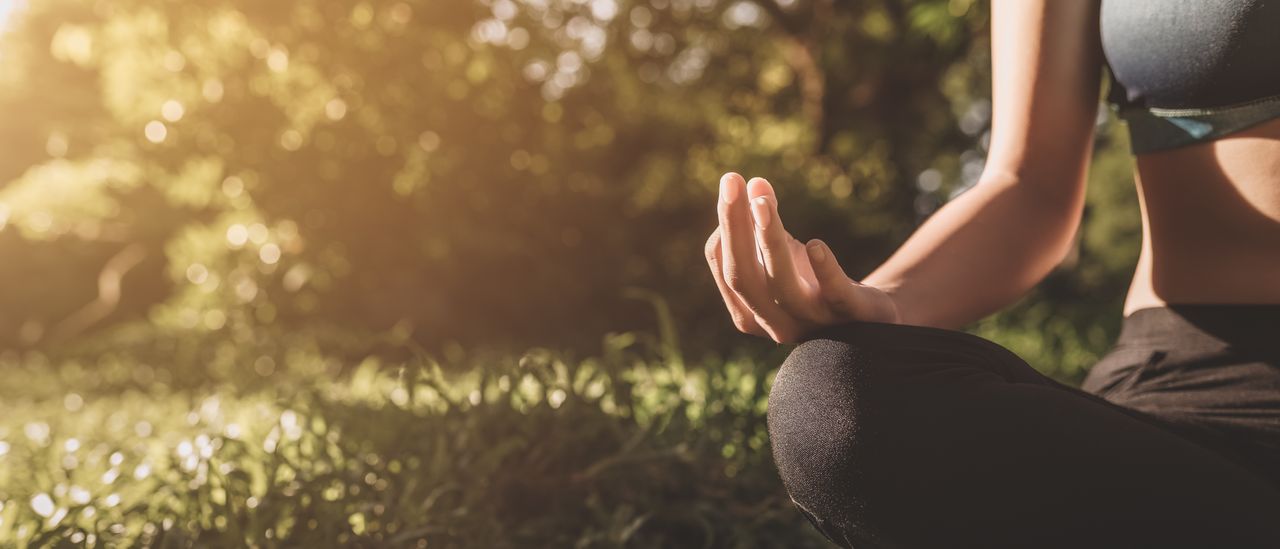Eine Frau bei übt Flow Yoga draußen auf einer Wiese