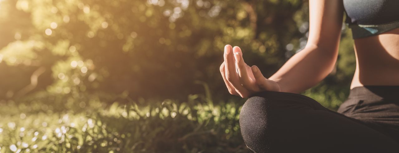 Eine Frau bei übt Flow Yoga draußen auf einer Wiese