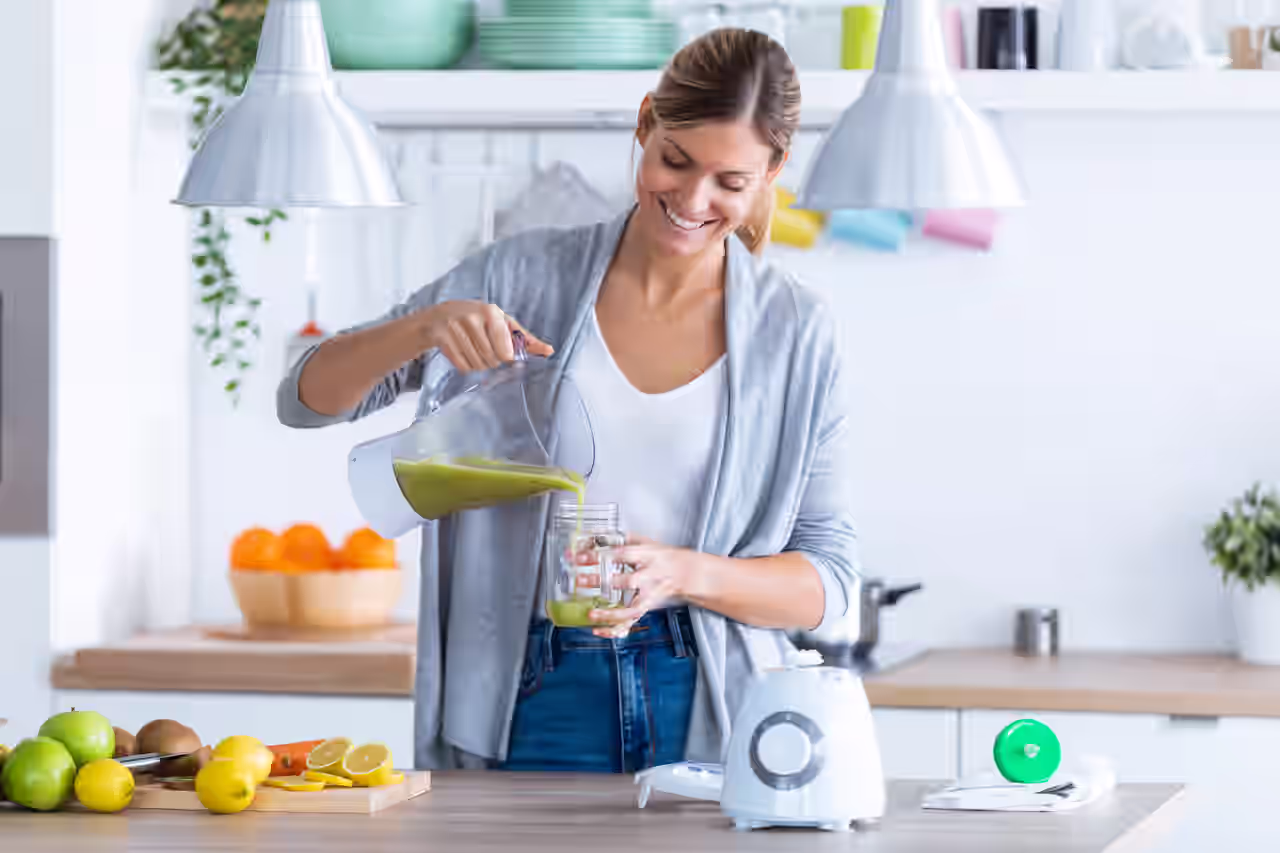 Lächelnde Frau gießt sich einen frischen Smoothie ein