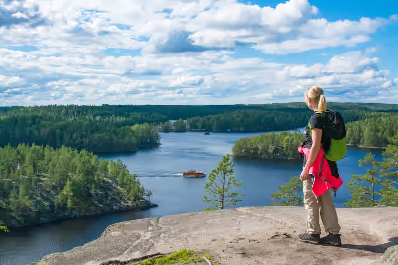 Eine Frau wandert und genießt die Aussicht von einer hohen Klippe in einem Nationalpark in Finnland.