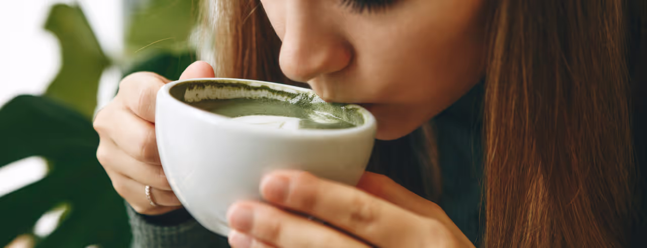 Eine Frau trinkt genüsslich Matcha