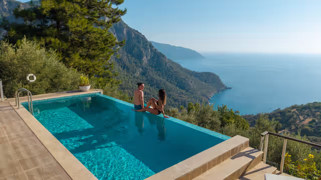 Ein Paar entspannt im Pool mit Panoramablick übers Meer