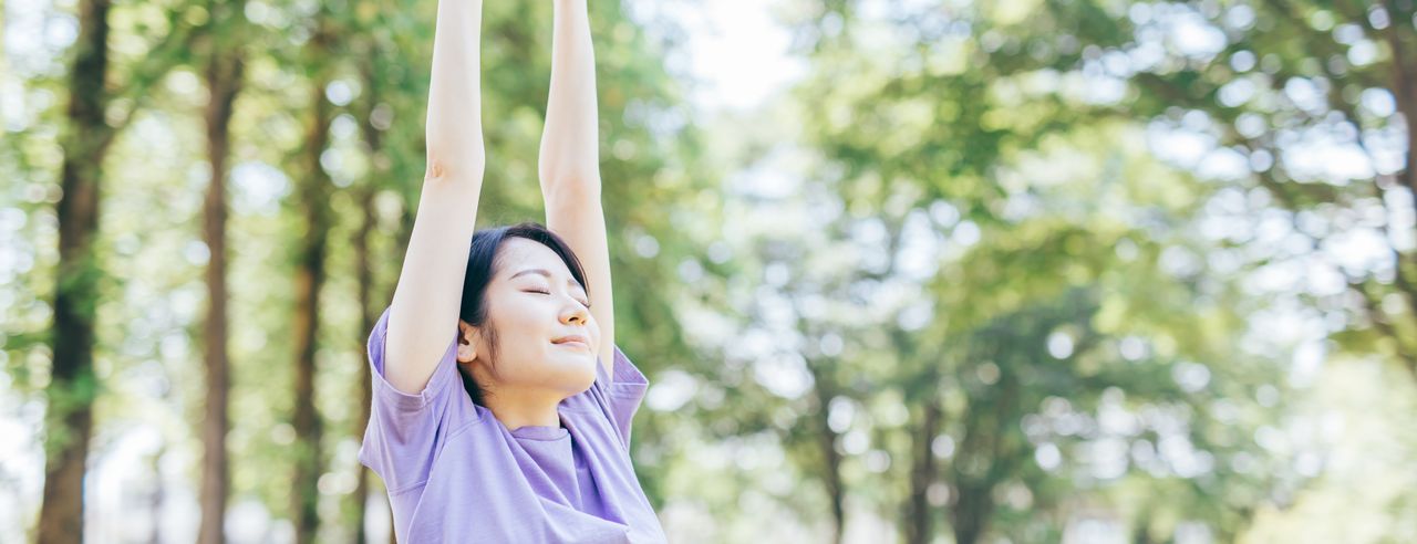 Kobieta wyciąga ręce do góry w zrelaksowany sposób