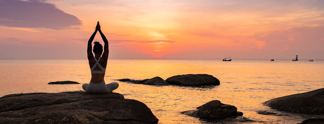 Frau meditiert auf Felsen am Meer