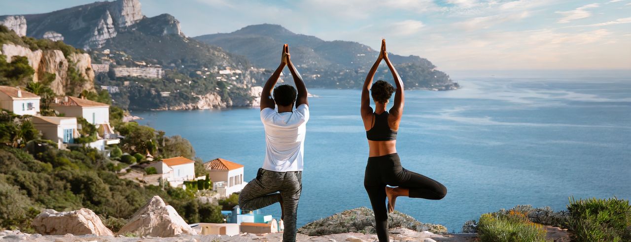 Ein Paar übt Yoga vor der traumhaften Kulisse der Côte d'Azur