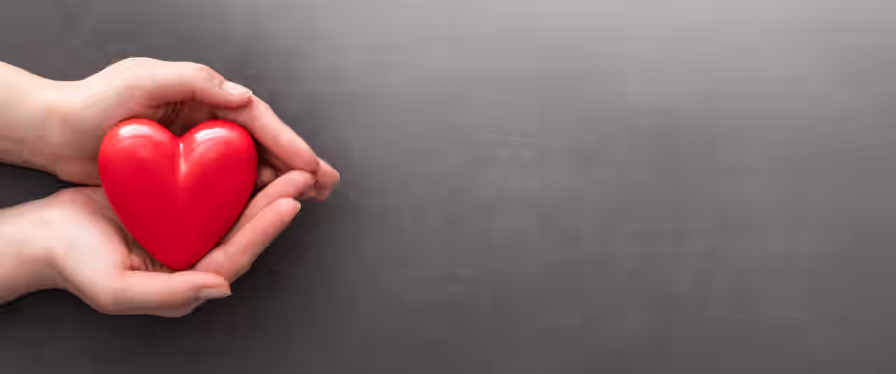 Zwei Hände halten ein Herz vor einem grauen Hintergrund