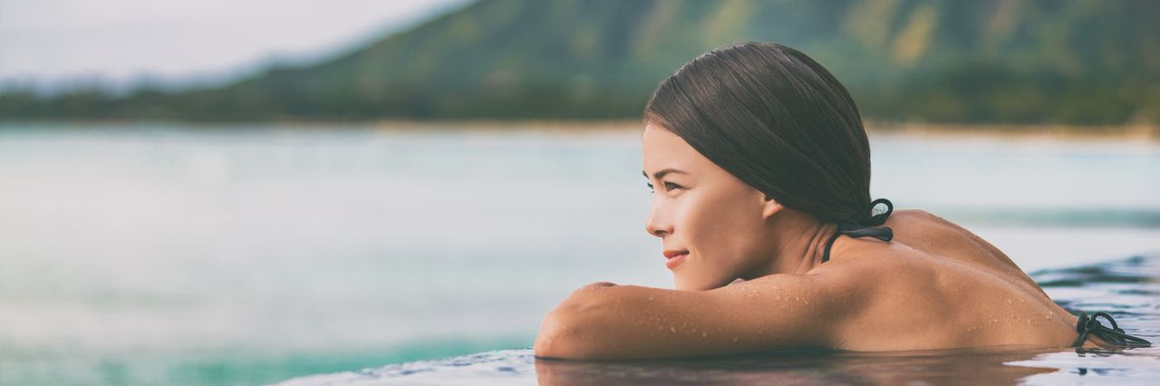 Eine Frau im Infinity Pool am Meer