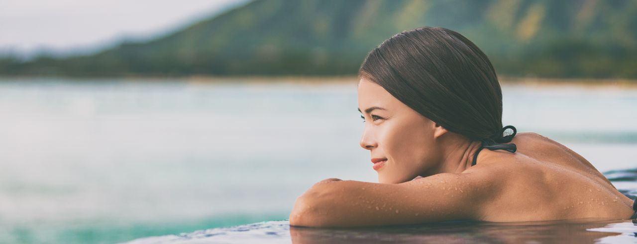 Eine Frau im Infinity Pool am Meer