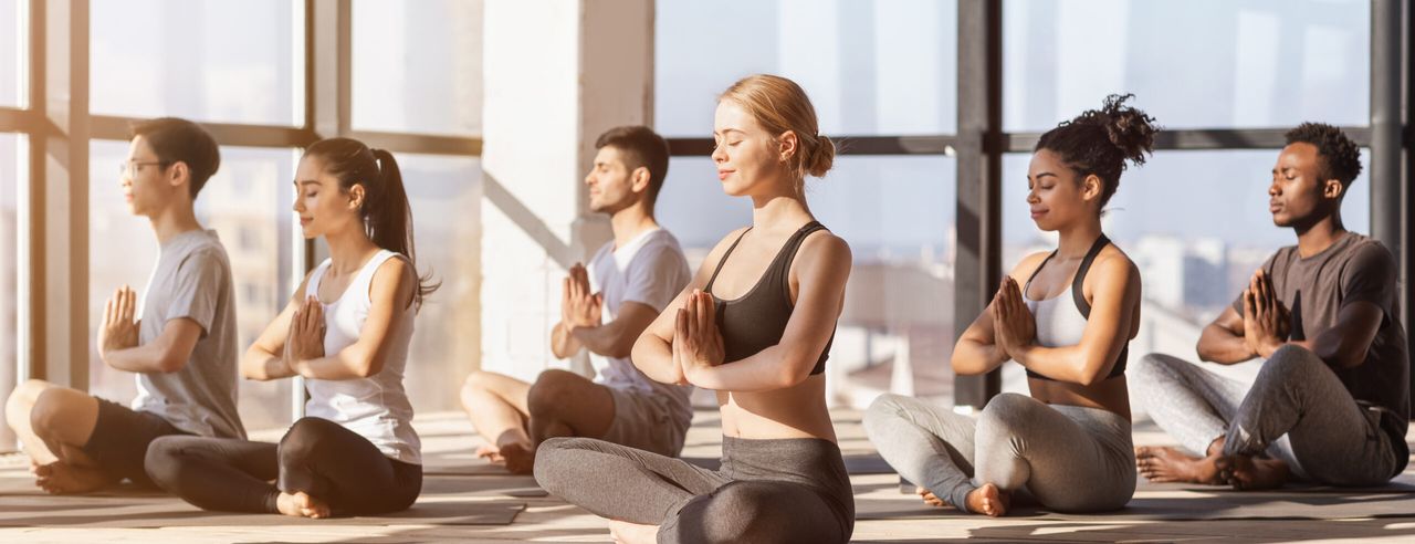 Eine Gruppe übt Yoga im hellerleuchteten Yoga Studio