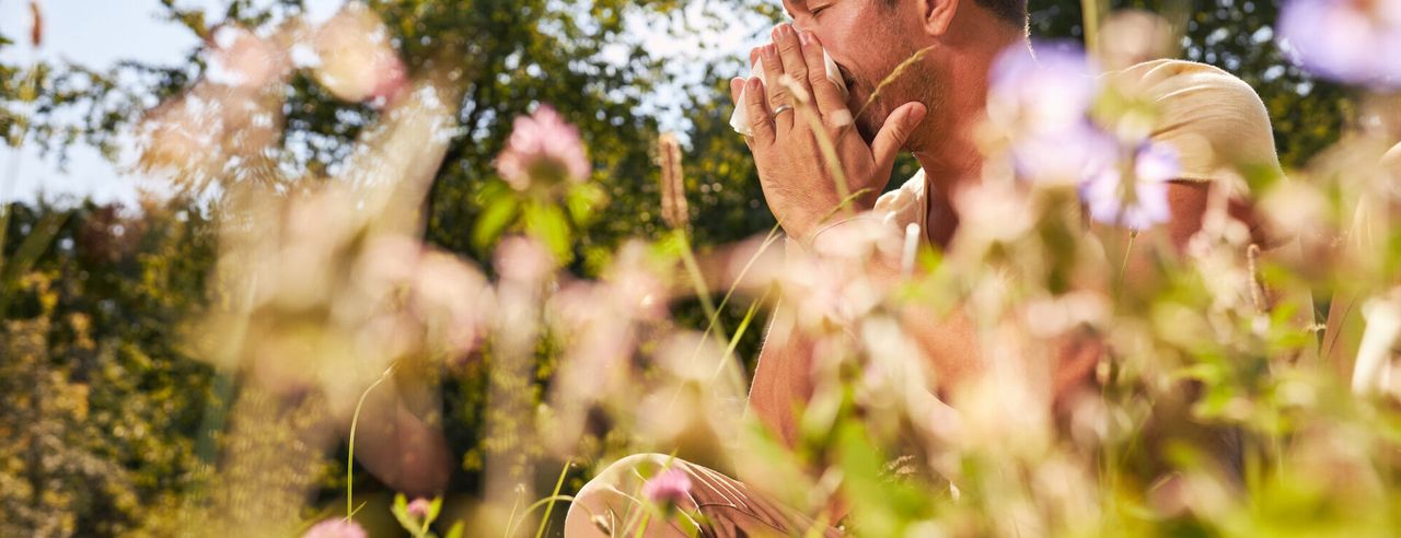 Mann mit Heuschnupfen putzt sich die Nase