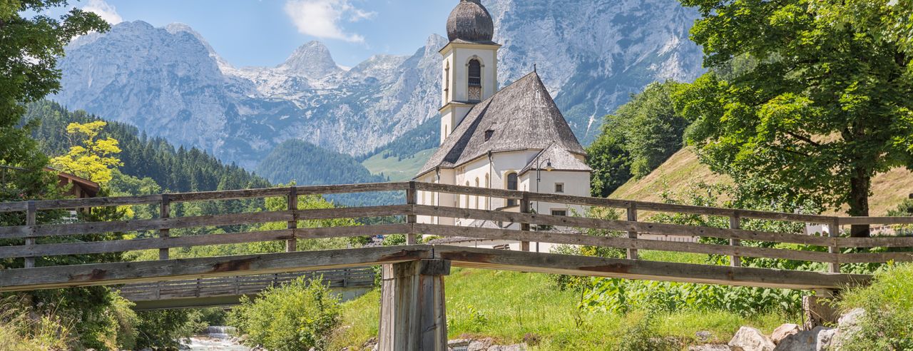 Kleine Kirche hinter Brücke. neben Fluss im Wald