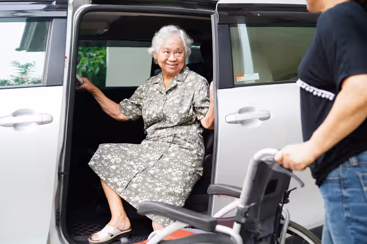 Eine ältere Dame im Rollstuhl wird vom Shuttle abgeholt