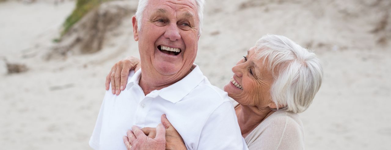 Senioren Paar umarmt sich lachend am Strand