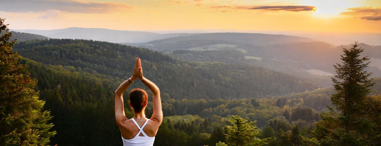 Eine Frau macht Yoga vor der schönen Landschaft des Erzgebirges