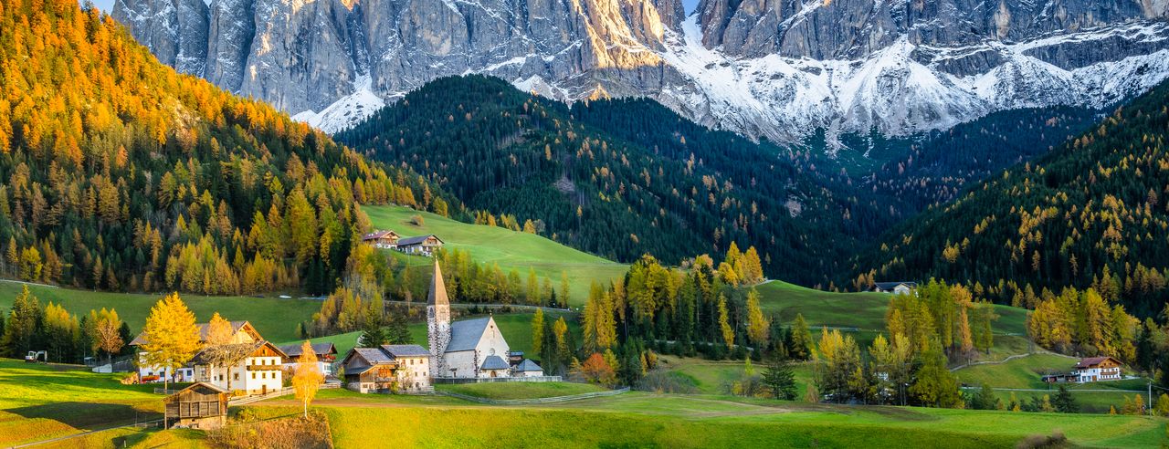 Die schöne Bergwelt im Hintergrund. Im Vordergrund satte grüne Wiesen.