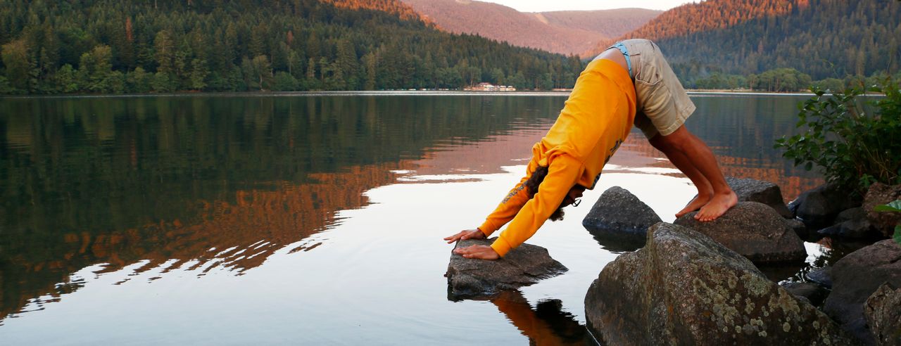 A man does yoga in the mountains by a lake