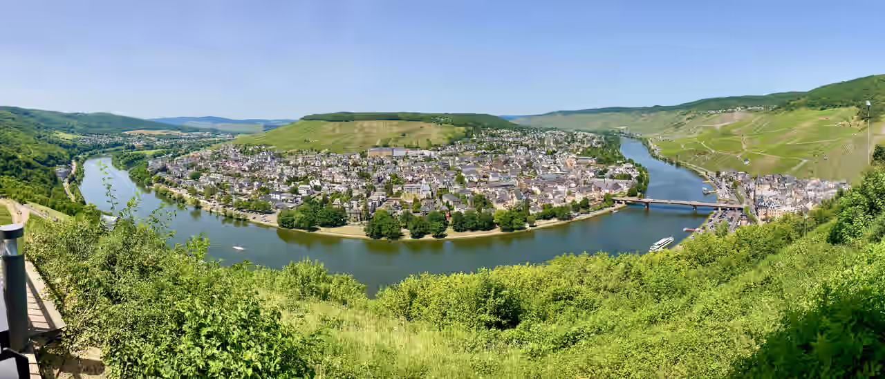 Blick vom Berggipfel über die Mosel auf eine Stadt im Tal