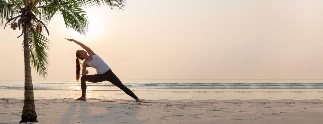 Frau in der Triangel-Yoga-Pose am Strand
