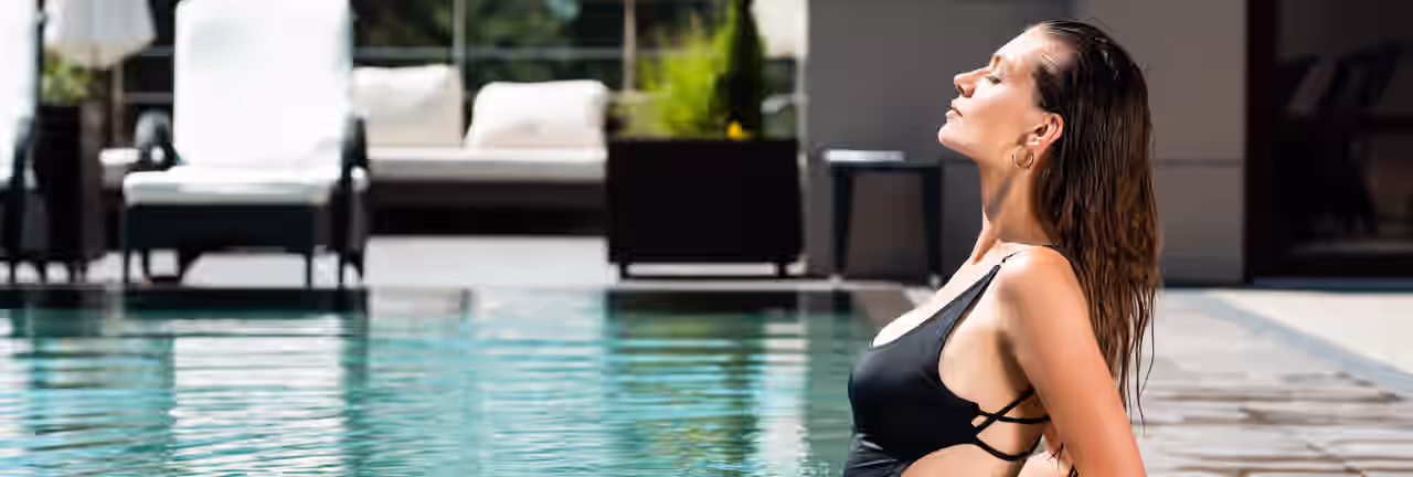 Eine Frau entspannt am Beckenrand eines Pools