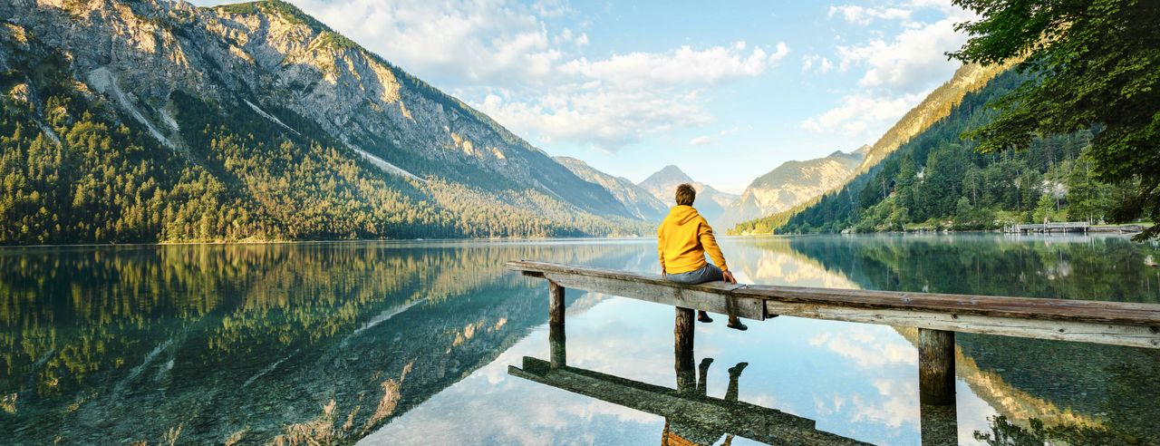 Ein Mann auf einem Holzsteg am Bergsee