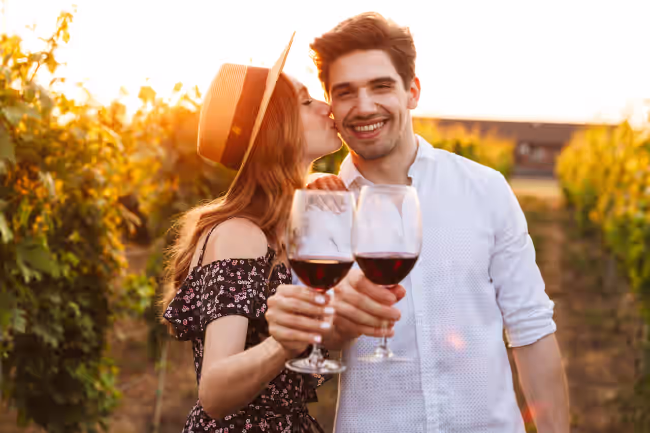Ein glückliches Paar mit Rotwein auf einem Weinberg