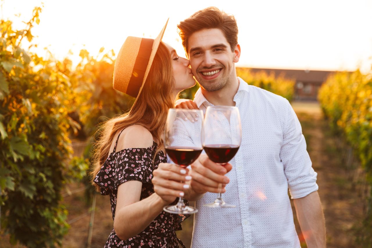 Ein glückliches Paar mit Rotwein auf einem Weinberg