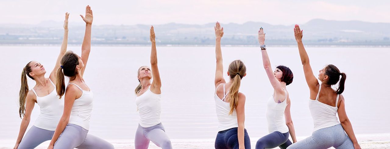 Eine Gruppe sportlicher Frauen macht Pilates am See