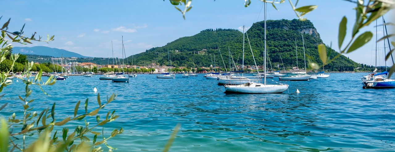 Ausblick auf den Gardasee mit Segelboten und Bergen im Hintergrund