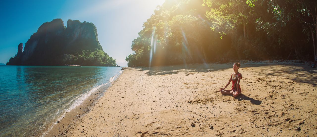Eine Frau meditiert am Meer